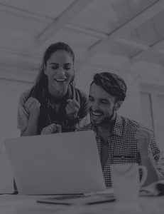 Standing woman and sitting man smiling at a laptop